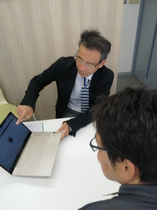 パソコンを見ながら打ち合わせをする桃井正行